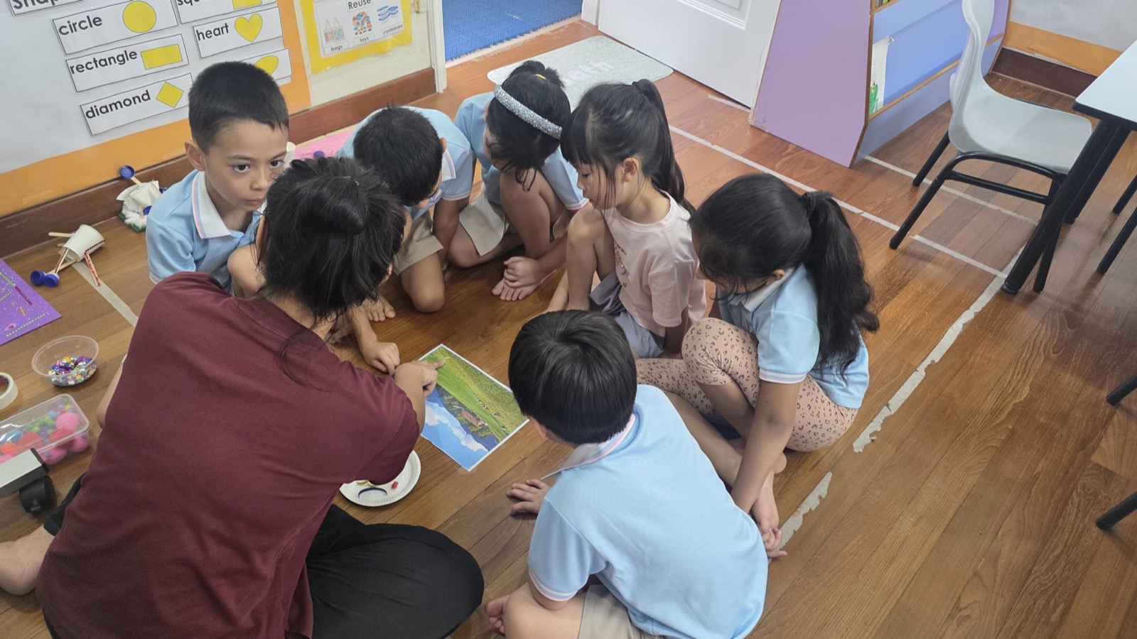 Genius Gems children gathered around their teacher for a small-group lesson, preparing for primary school